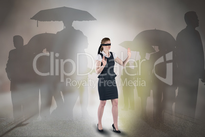 Composite image of redhead businesswoman in a blindfold