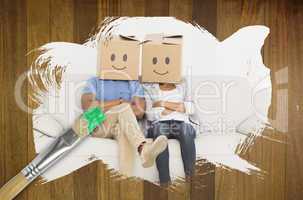 Composite image of couple wearing boxes on head