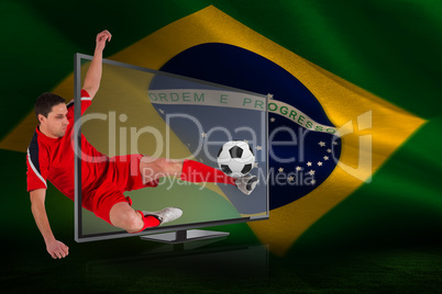 Fit football player kicking ball through tv