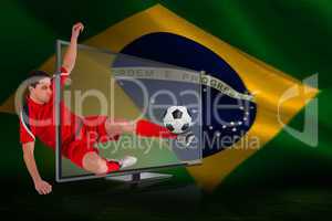 Fit football player kicking ball through tv