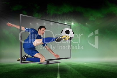 Fit football player kicking ball through tv