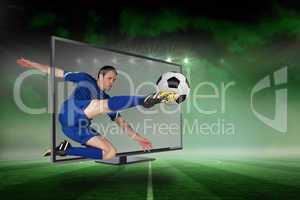 Fit football player kicking ball through tv