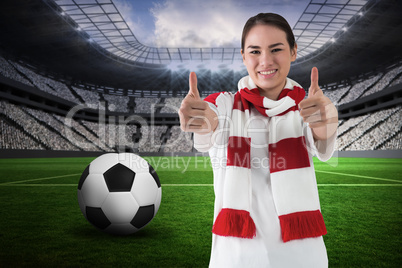 Football fan in white wearing scarf showing thumbs up