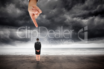 Giant hand pointing at young businesswoman standing with hands b