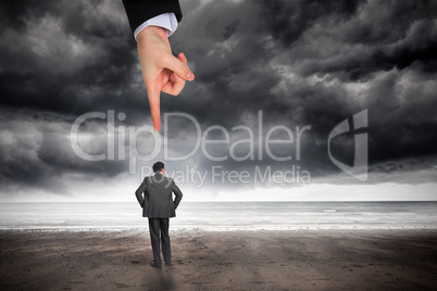 Giant hand pointing at businessman with hands on hips