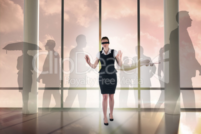 Composite image of redhead businesswoman in a blindfold