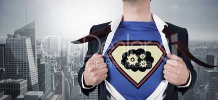 Composite image of businessman opening shirt in superhero style