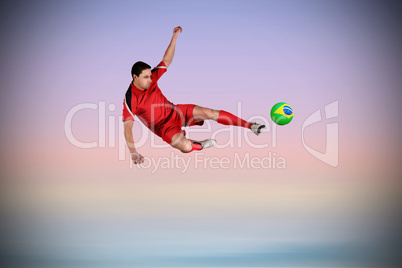 Fit football player jumping and kicking