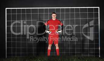 Composite image of goalkeeper in red looking at camera