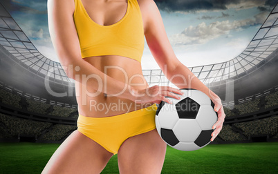 Composite image of fit girl in yellow bikini holding football
