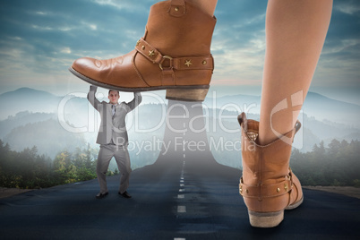 Composite image of cowboy boots stepping on businessman