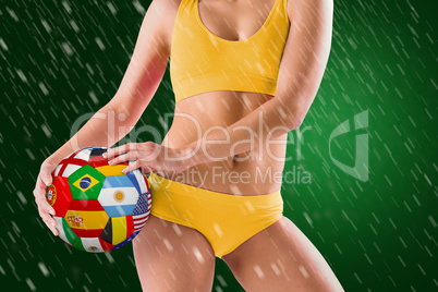 Composite image of fit girl in yellow bikini holding flag footba