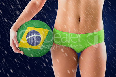 Composite image of fit girl in green bikini holding brazil footb