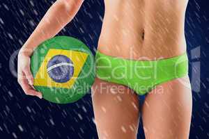 Composite image of fit girl in green bikini holding brazil footb