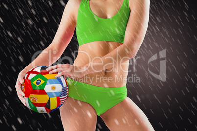 Composite image of fit girl in green bikini holding flag ball