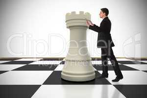 Composite image of businessman in suit pushing chess piece