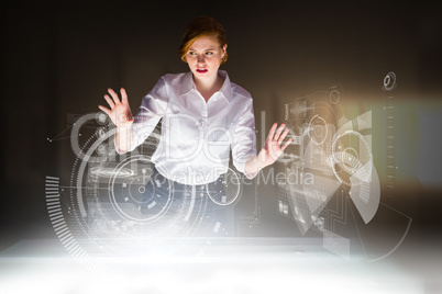 Composite image of redhead businesswoman using interactive desk