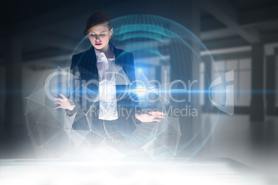 Composite image of redhead businesswoman using interactive desk