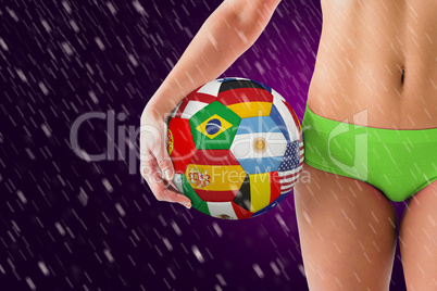 Composite image of fit girl in green bikini holding flag footbal