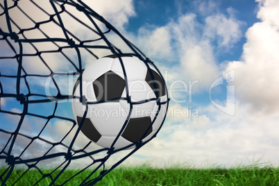 Composite image of football in back of the net