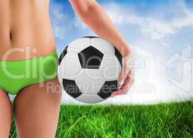 Composite image of fit girl in green bikini holding football