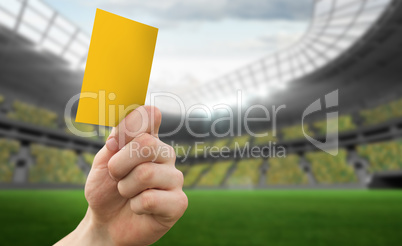 Composite image of hand holding up yellow card