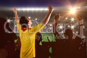Composite image of cheering football fan in yellow jersey