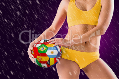 Composite image of fit girl in yellow bikini holding flag footba