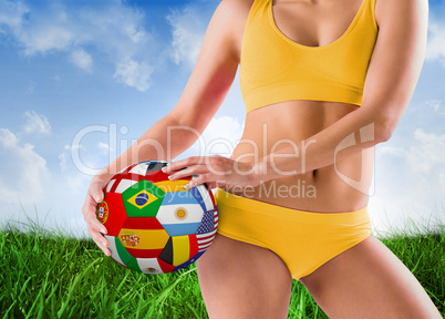 Composite image of fit girl in yellow bikini holding flag footba