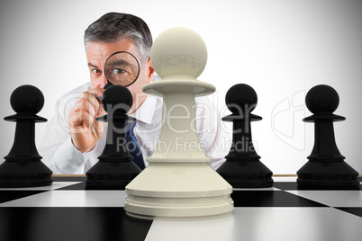 Composite image of focused businessman with magnifying glass