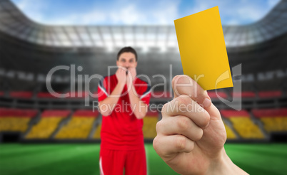 Composite image of hand holding up yellow card