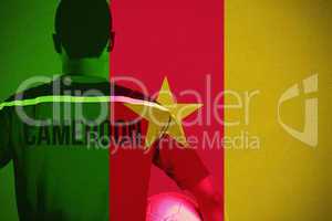 Composite image of cameroon football player holding ball