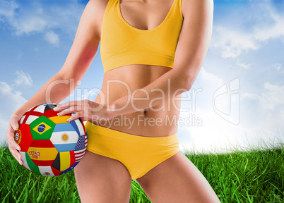 Composite image of fit girl in yellow bikini holding flag footba