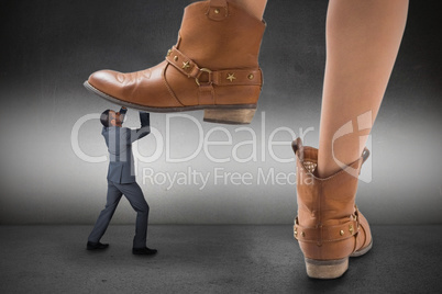 Composite image of cowboy boots stepping on businessman