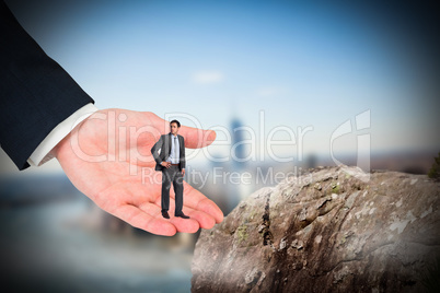 Composite image of serious businessman with hand on hip in large