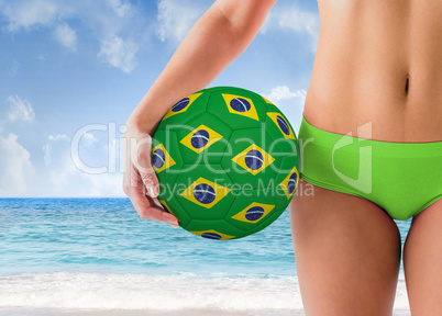 Composite image of fit girl in green bikini holding brazil footb