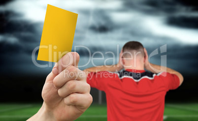 Composite image of hand holding up yellow card