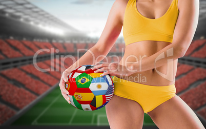 Composite image of fit girl in yellow bikini holding flag football