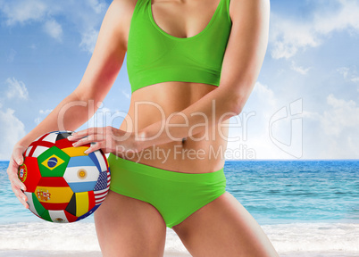 Composite image of fit girl in green bikini holding flag ball