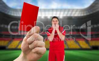 Composite image of hand holding up red card to player