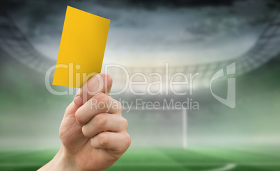 Composite image of hand holding up yellow card