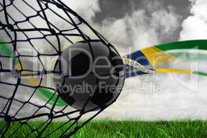 Composite image of football in back of the net