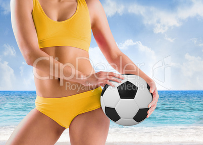 Composite image of fit girl in yellow bikini holding football