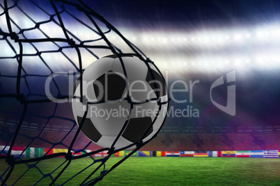 Composite image of football in back of the net