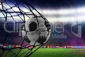 Composite image of football in back of the net