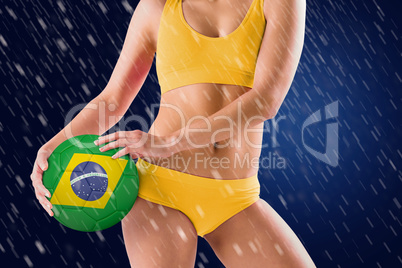 Composite image of fit girl in yellow bikini holding brazil foot