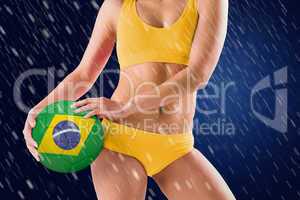 Composite image of fit girl in yellow bikini holding brazil foot