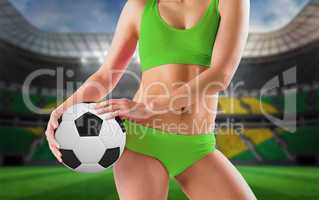Composite image of fit girl in green bikini holding football
