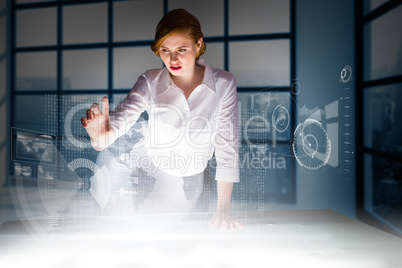 Composite image of redhead businesswoman using interactive desk