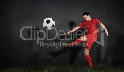 Composite image of football player in red kicking